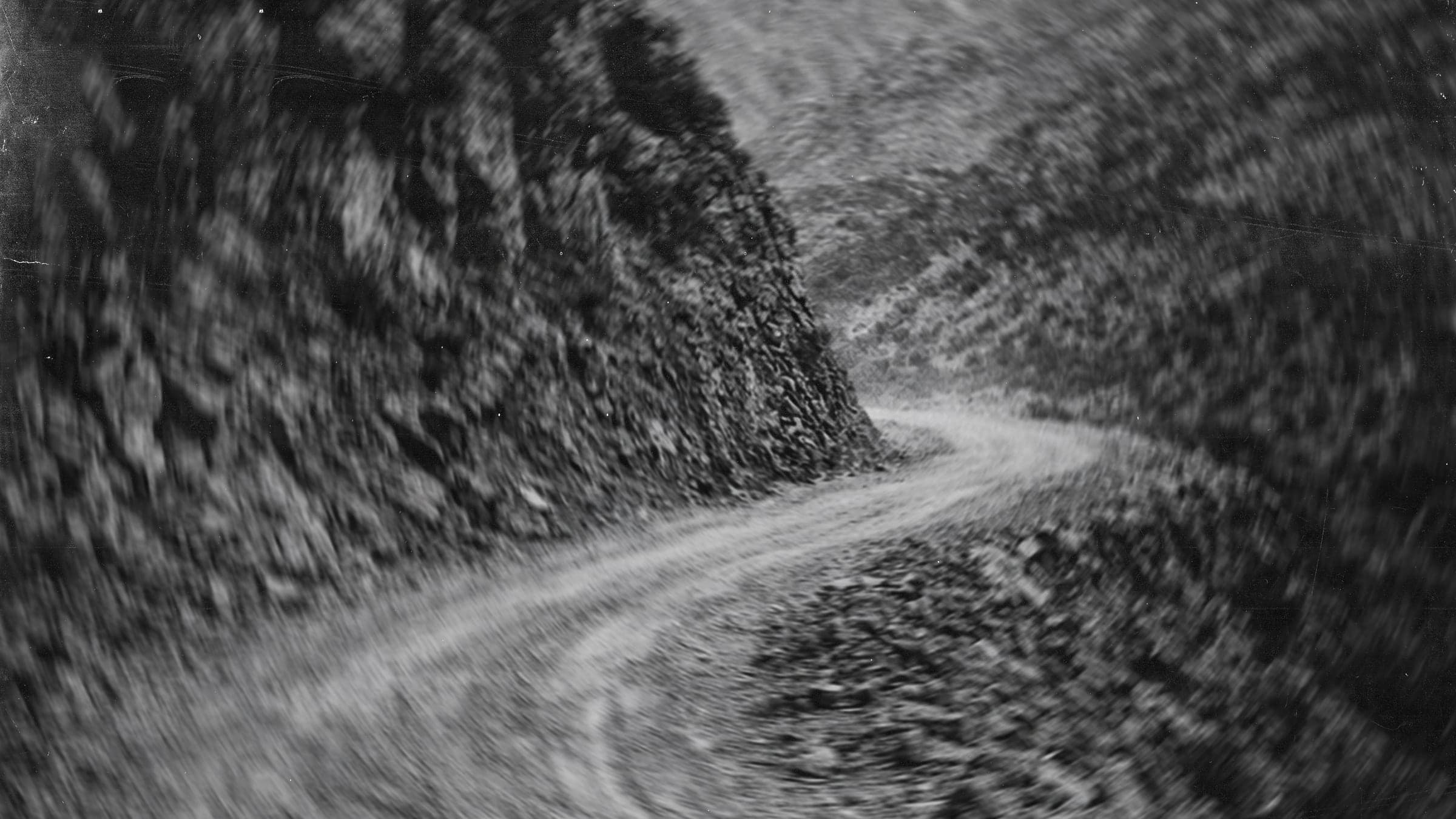 Black-and-white photograph of a dirt road cutting through hills, from the Kingswood site